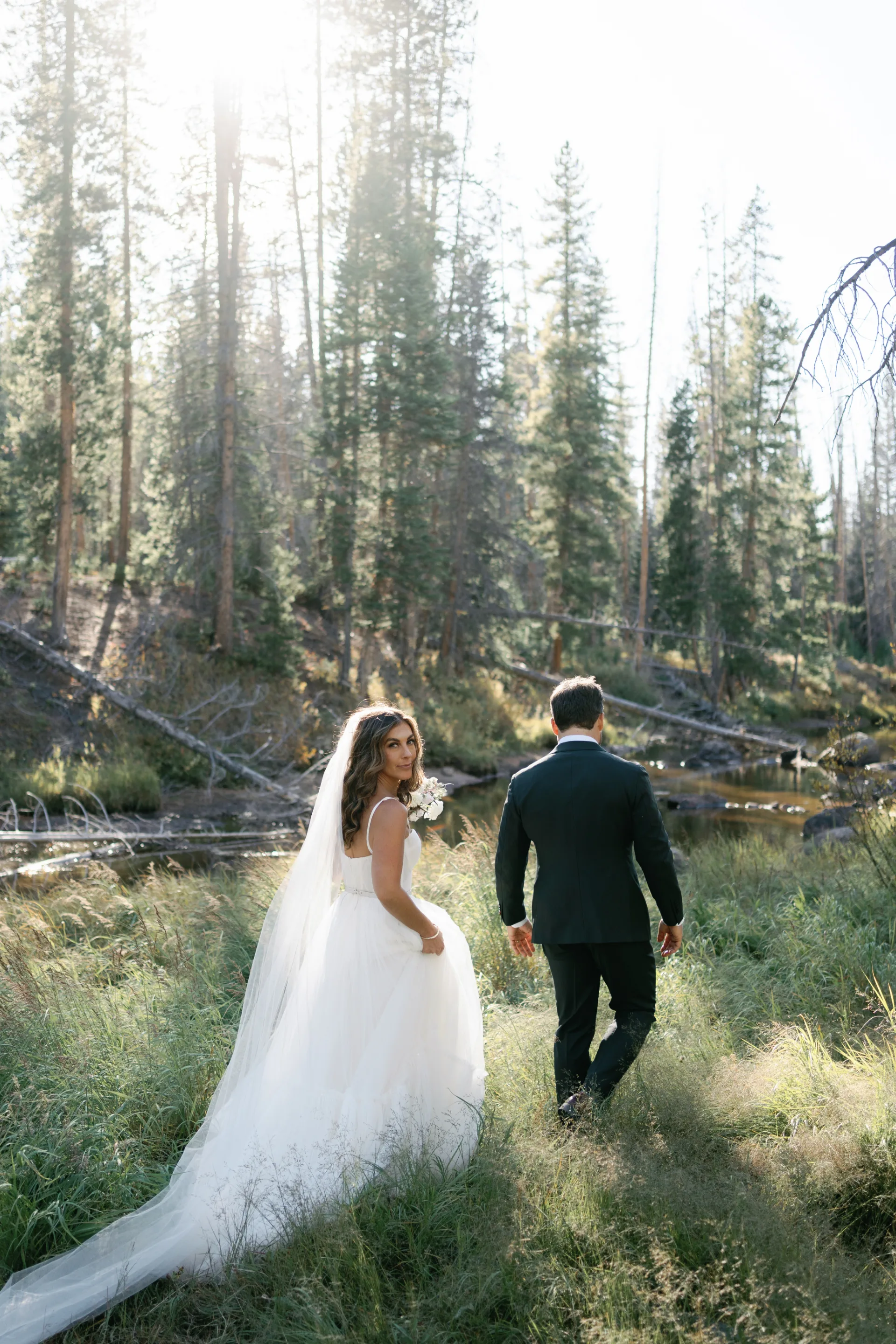 Bride and groom walking through the forest at Piney River Ranch